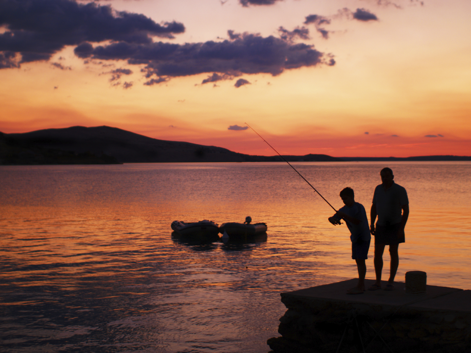 Two people fishing at sunset